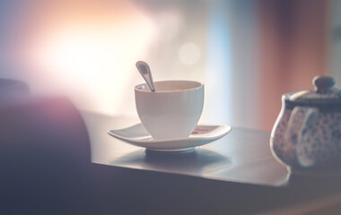 White ceramic coffee cup on dark surface and background with copy space Morning time. Blurry background focus on emotion warm and empty. Vintage tone filter effect color style.