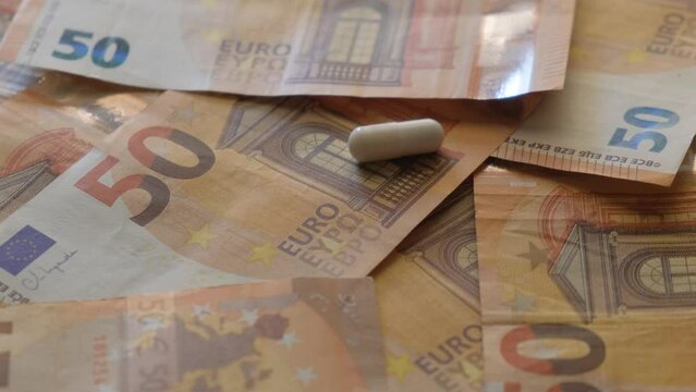 50 euro banknotes on the background. There are white pills. The concept of pharmaceutical corporations making money on treatment