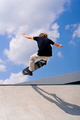 A young guy skater does a stunt on the edge of a skatepool against a backdrop of sky and clouds at a city skate park  © Guys Who Shoot