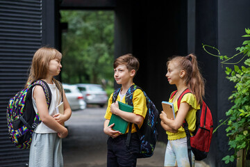 Three school children communicate and having fun outdoors. Classmates with backpacks. © Olha Tsiplyar