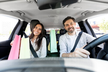 Cheerful spouses driving home after shopping in mall, talking, smiling