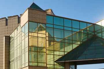 Obraz premium Upper part of corner of glass modern building with variety of stylish and geometric elements standing in downtown of city