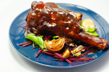 Delicious Lamb shank with red wine and rosemary gravy served on the mixed leaf salad, on the blue plate