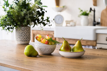 ripe pears and grape on plate on wooden dining table at kitchen
