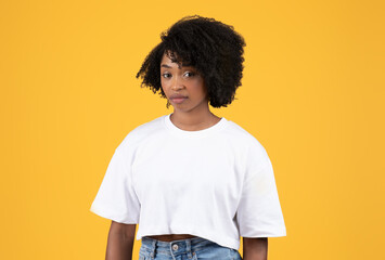 Unhappy serious pretty young black curly lady in white t-shirt look at camera