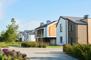 Perspective view of modern two storey village houses with small front yards surrounded by fence and...