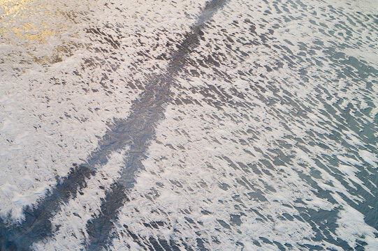 Abstract aerial view of snow remains with gaps on the ice of a frozen lake in winter, Reykjanes, Iceland.