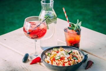 Bowl of french fries topped with sauce and refreshing drinks on a wooden table