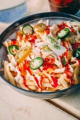Bowl of french fries topped with sauce