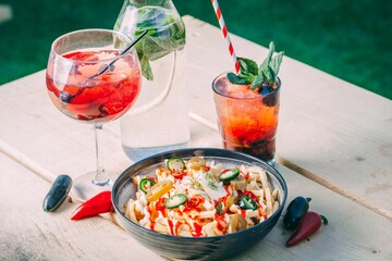 Bowl of french fries topped with sauce and refreshing drinks on a wooden table