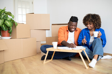 Fototapeta na wymiar Smiling Black Spouses Making Checklist After Moving To New Home