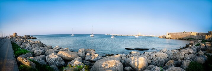 Panoramic shot of multiple sailboats docked along the tranquil shoreline of a tranquil bay