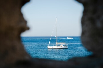 Large cruise liner sailing on the tranquil blue waters of the ocean seen through rocks