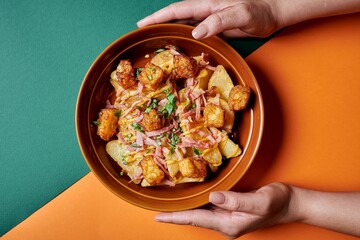 a bowl filled with potatoes, ham and gravy on top of an orange