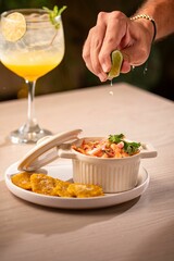 Adult male squeezing a lime into a white pot filled with a fresh Venus salad