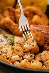 Stainless steel fork on a selection of steaming fried shrimp and other tasty ingredients