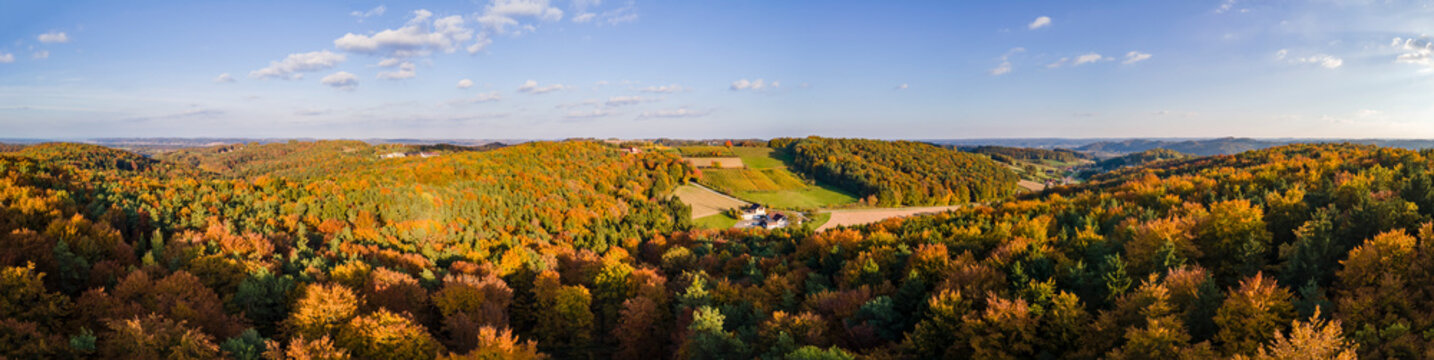 Aerial drone panoramic view of the autumn colours as the sun sets in the hill country on the border of Burgenland and Styria under scattered clouds, Bad Loipersdorf, Styria, Austria.