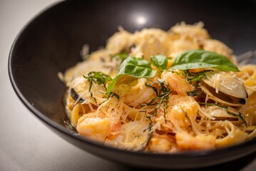 the bowl is full of noodles and prawle, topped with herbs
