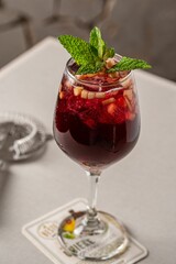 Vertical shot of a glass of delicious sangria with mint garnish on the table