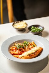 Bowl of delicious penne pasta with cheese and sauce on the table