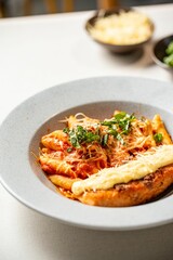 Bowl of delicious penne pasta with cheese and sauce on the table