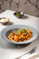 Bowl of delicious fresh pasta with meat, sauce, and cheese on the table