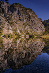 a mountain peak reflected in a small lake surrounded by hills