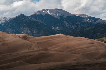 Naklejka premium Great Sand Dunes National Park, featuring sandy dunes with a mountain and sky backdrop