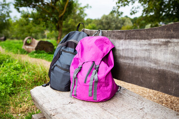 Two bright backpacks stand on a wooden bench in the street. Outdoor recreation. Trekking in the mountains, couple on vacation.