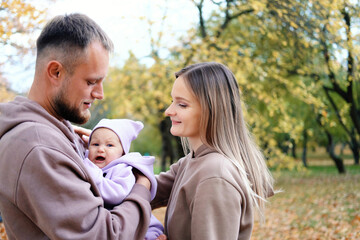 Fototapeta premium Parents on a walk with a baby in the autumn park. The baby is crying and screaming.