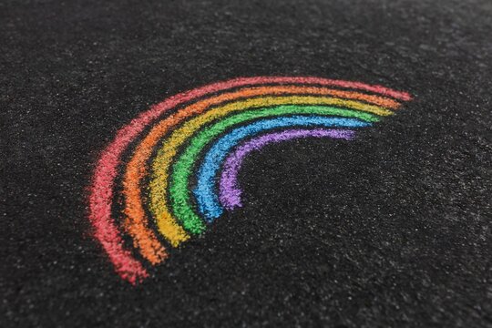 Close-up of a rainbow painted on a road with sidewalk chalk, shot from above
