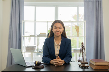 Asian female lawyer in formal dress Work with laptops and law books, hammers and scales, real estate work and dispute contract documents for defense strategies. Fight for freedom 