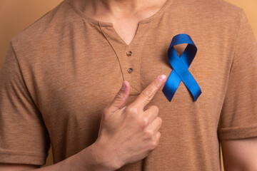 detail hands of brazilian man showing blue ribbon in beige background. prostate cancer, awareness...