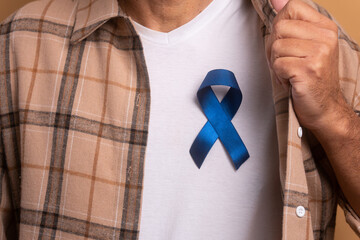 anonymous brazilian man showing blue ribbon in studio shot. prostate cancer, awareness concept.