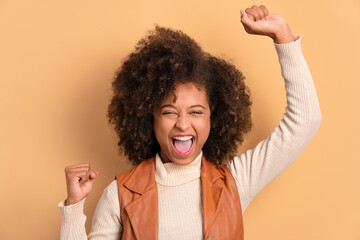 fun black young woman raising arms and celebrating in all beige colors. celebration, positive,...