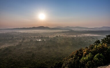 a large rock with a mountain in the background and mist in the air
