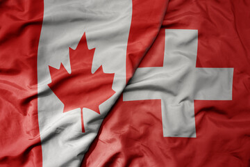 big waving realistic national colorful flag of canada and national flag of switzerland .