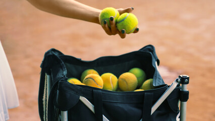 young woman taking balls out of a bag on a tennis court