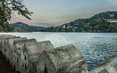Tranquil lake surrounded by lush green foliage, rolling hills and picturesque buildings