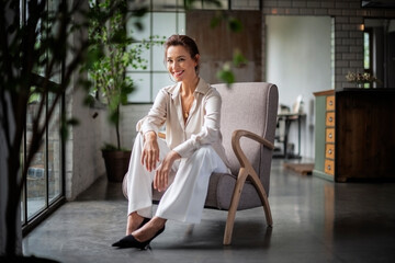 A mid aged woman sitting in an armchair and cheerful smiling