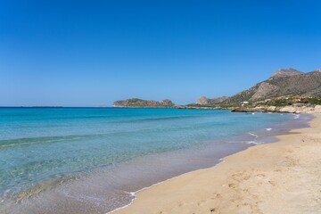 Tranquil scene of blue waters lapping against a beach with mountains in the background in Greece