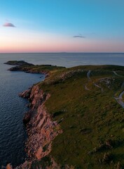 Naklejka premium a cliff overlooks the ocean and the sky as a sun rises above it