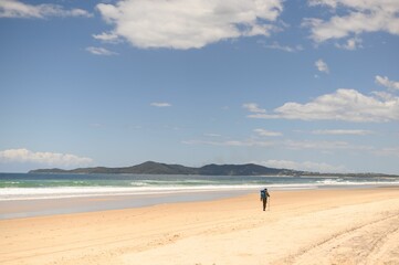 Fototapeta na wymiar Man walking along a sun-soaked Noosa Beach, Australia