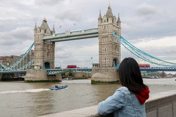 Foto op Plexiglas Londen rode bus Female Tourist in London, looking at famous and iconic sights of the city as red buses cross the Tower Bridge, on the banks of the River Thames