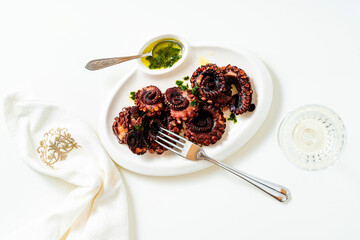 boiled octopus on a plate with green sauce. served with white wine