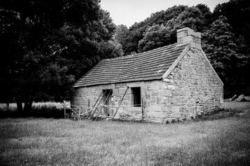 Grayscale shot of a stone building in a field in Bretagne, France