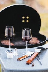 Vertical shot of a table near a grill with wine glasses and spatulas