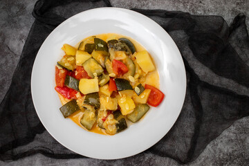 cooking tasty vegetable mix with courgette, red pepper, potato and tomato on plate