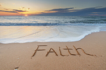 Faith word on the sea shore during sunset.