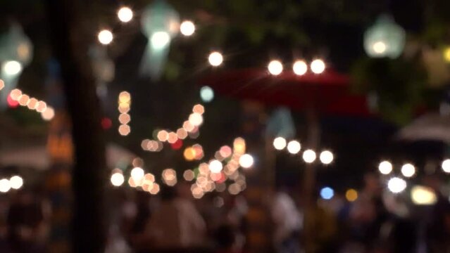 Blur bokeh evening night bazaar festival in yard garden traditional fair fun vibe light and people Thailand Summer